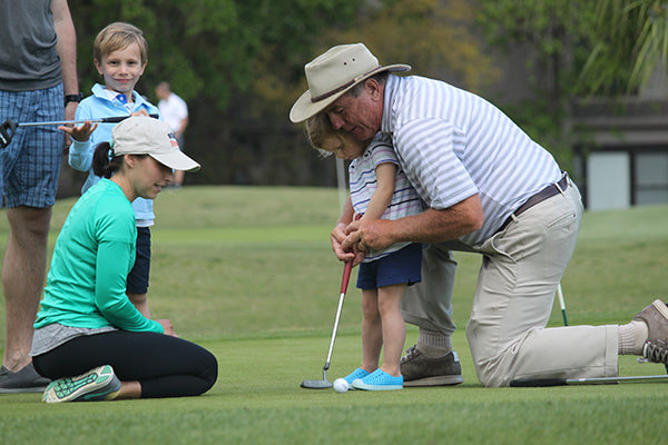 A man teaching a kid how to putt