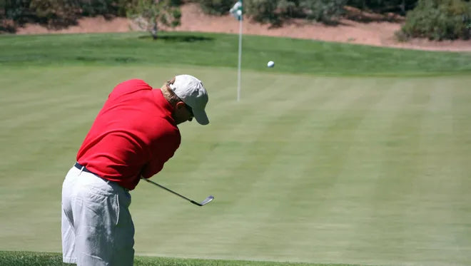 Man hitting a golf ball on the green